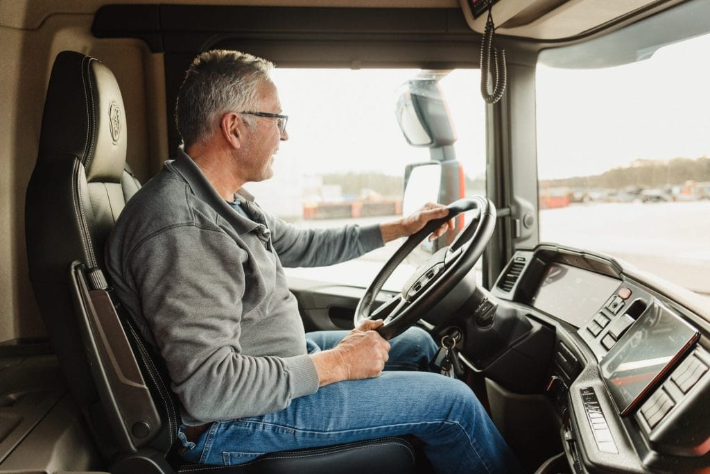 Jan, vrachtwagenchauffeur, rijdt veilig op de snelweg in zijn vrachtwagen.