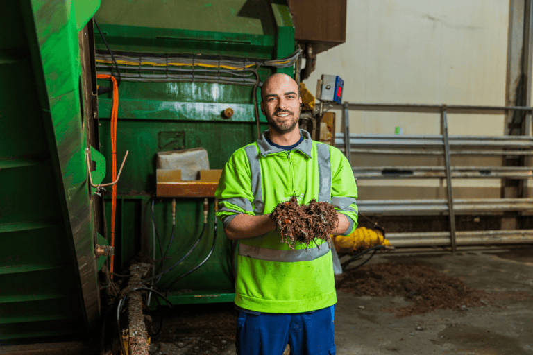 Jimmy, procesoperator, houdt organisch materiaal vast in een industriële omgeving.