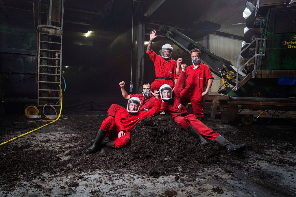 Team van werknemers in productiehal met Youri, leidinggevende, in rode bedrijfskleding.
