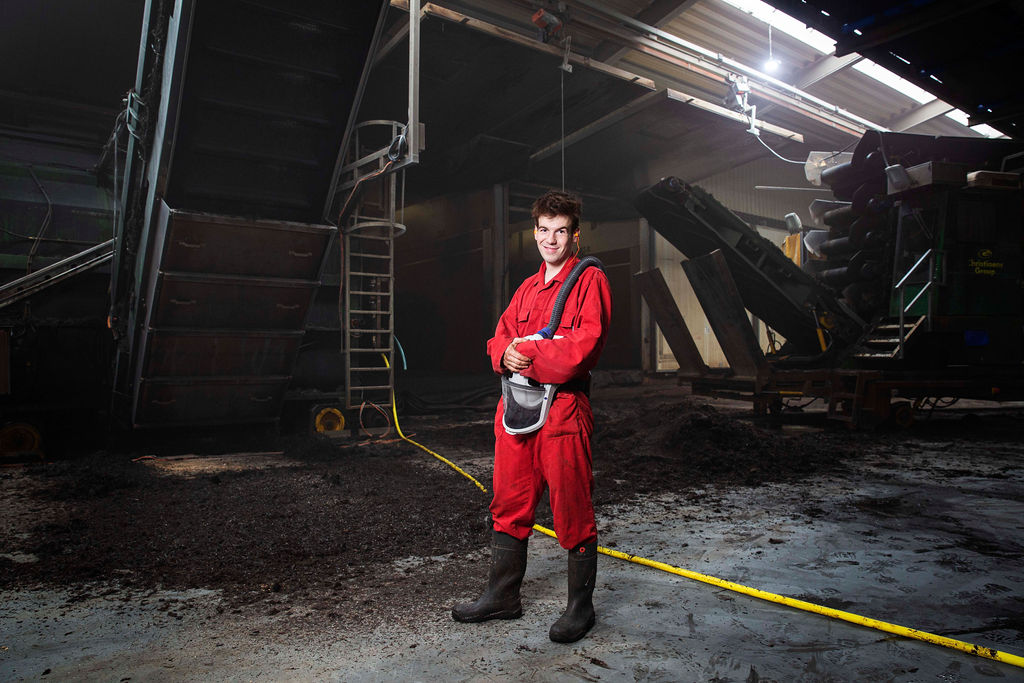 Productiehal leidinggevende in veiligheidskleding en helm in een industriële omgeving.