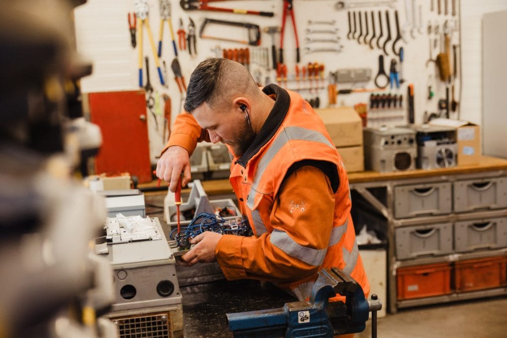 Elektricien voert onderhoud uit aan elektrische installaties in een werkplaats.