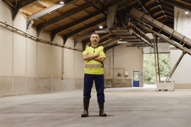 Man in veiligheidskleding in grote industriële hal.
