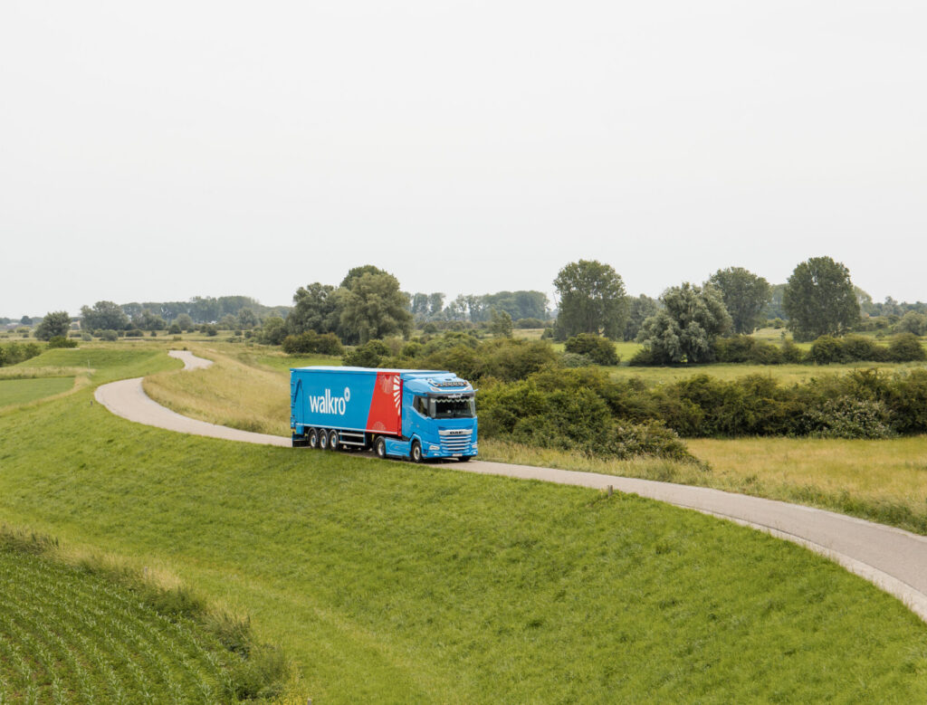 Walkro vrachtwagen rijdt door groen landschap op landelijke weg.